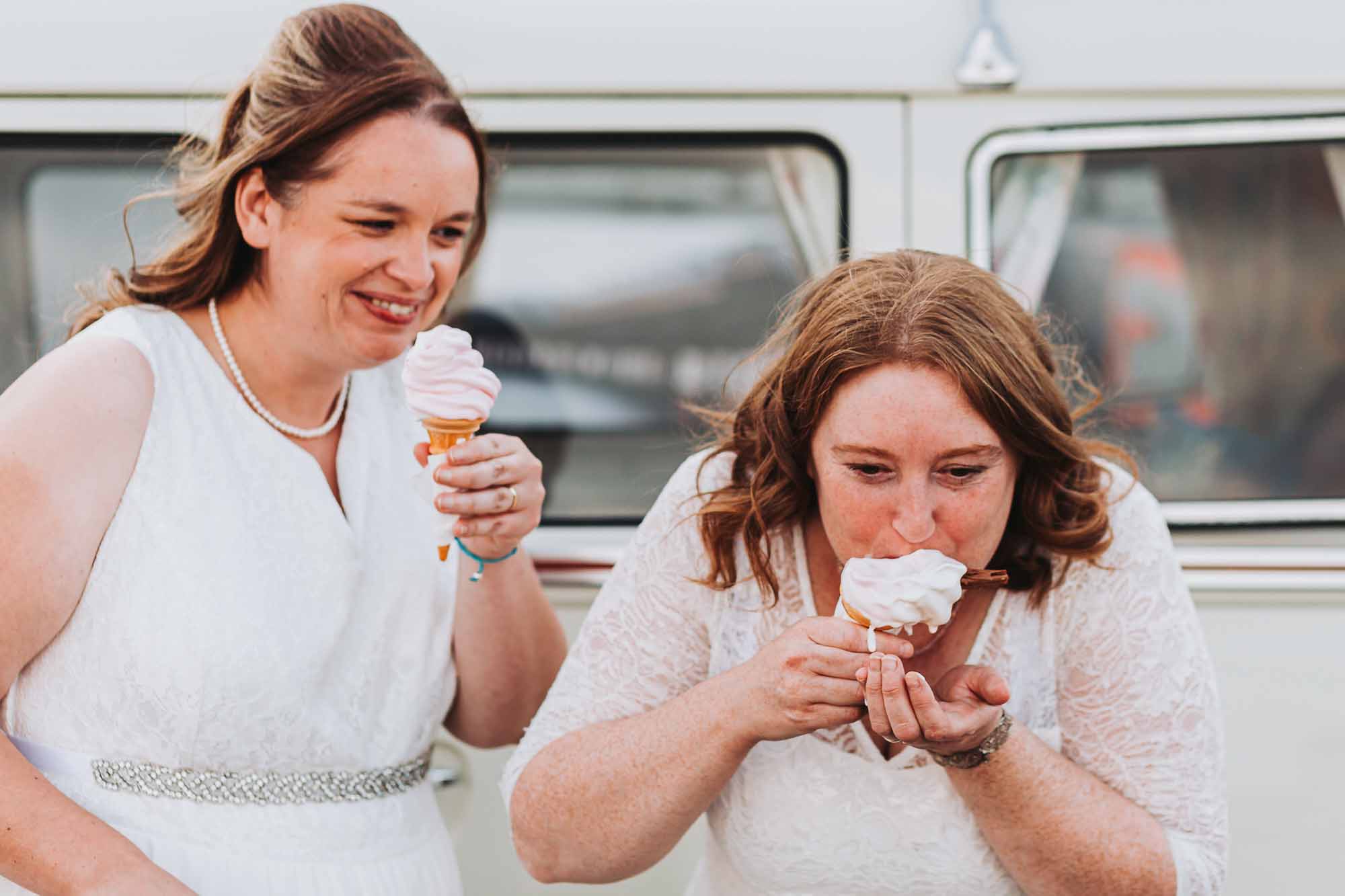 two bride laughing and messily eating ice cream