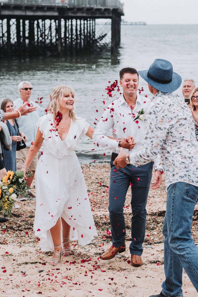 confetti thrown over bride and groom on beach
