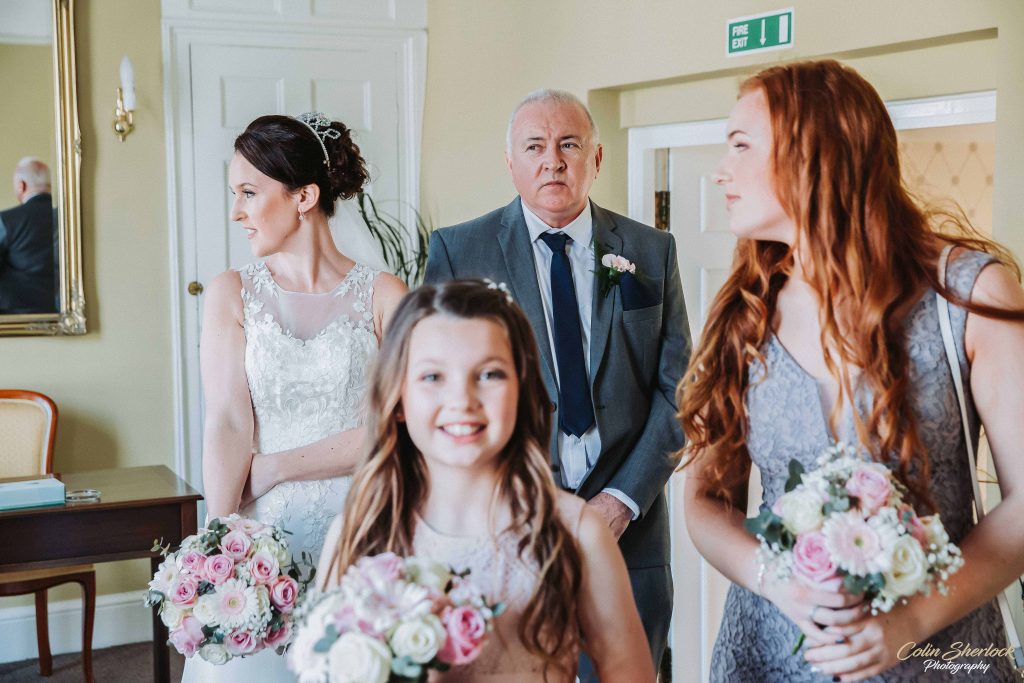 bride waiting to enter wedding ceremony with father and bridesmaids