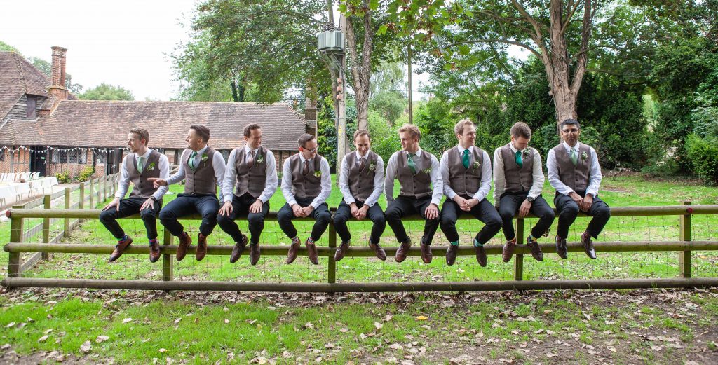 groom and groomsmen on fence at chilham village hall