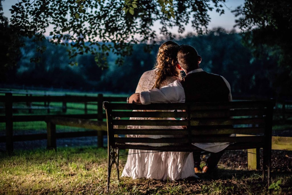 bride and groom on bench looking over fields