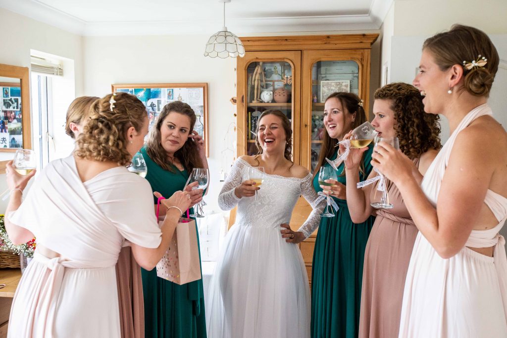 bride and bridesmaids drinking champagne and laughing