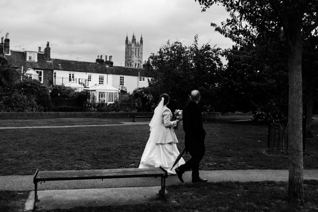 bride and groom walking together looking at Canterbury cathedral in the distance