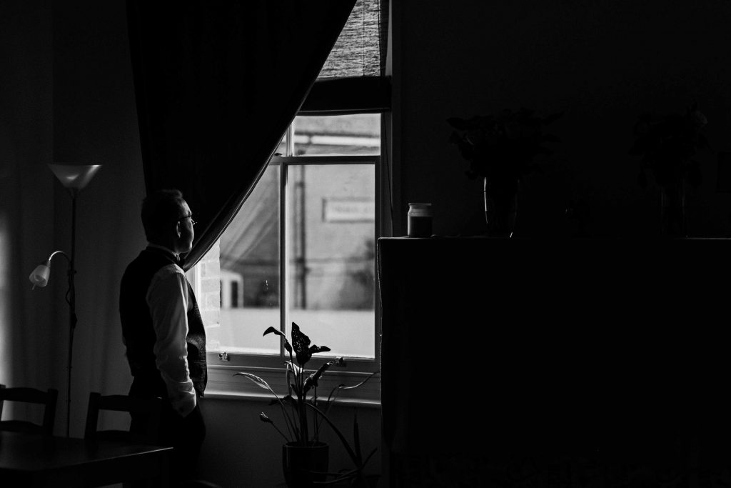Groom looking out the window in pensive thought