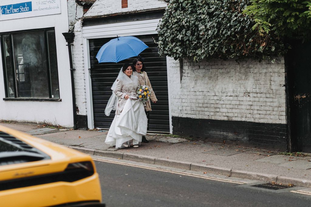 bride with bridesmaid walking with umbrella in rain