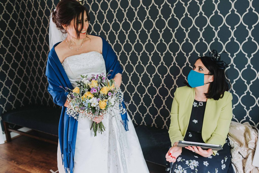 bride with bouquet and bridesmaid with mask in registry office