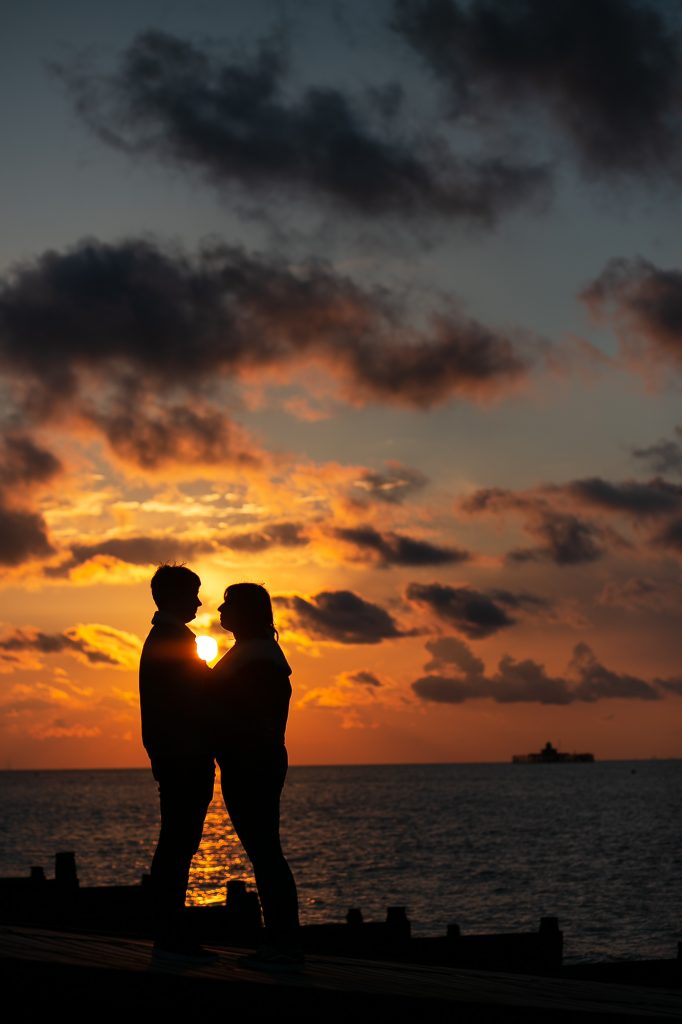 couple silhouette against sunset on the coast