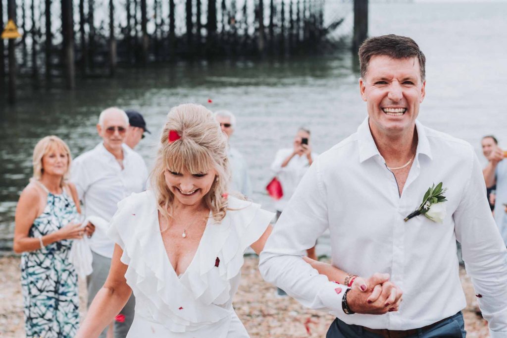 confetti being thrown over bride and groom on beach