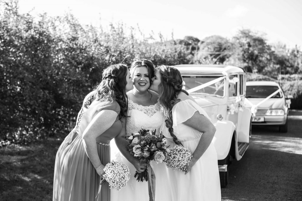 bride being kissed by her bridesmaids