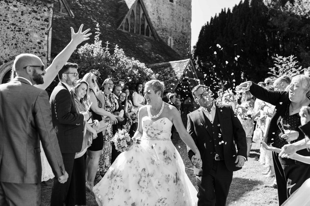 bride and groom having confetti thrown at them outside of church