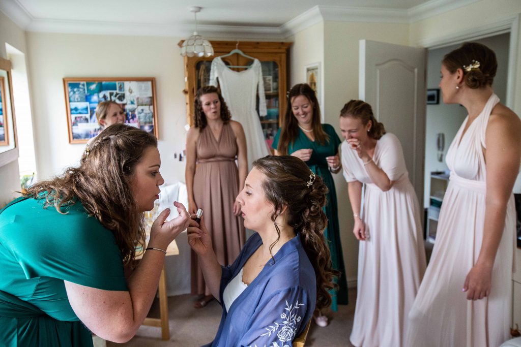 bride with bridesmaids helping her with makeup