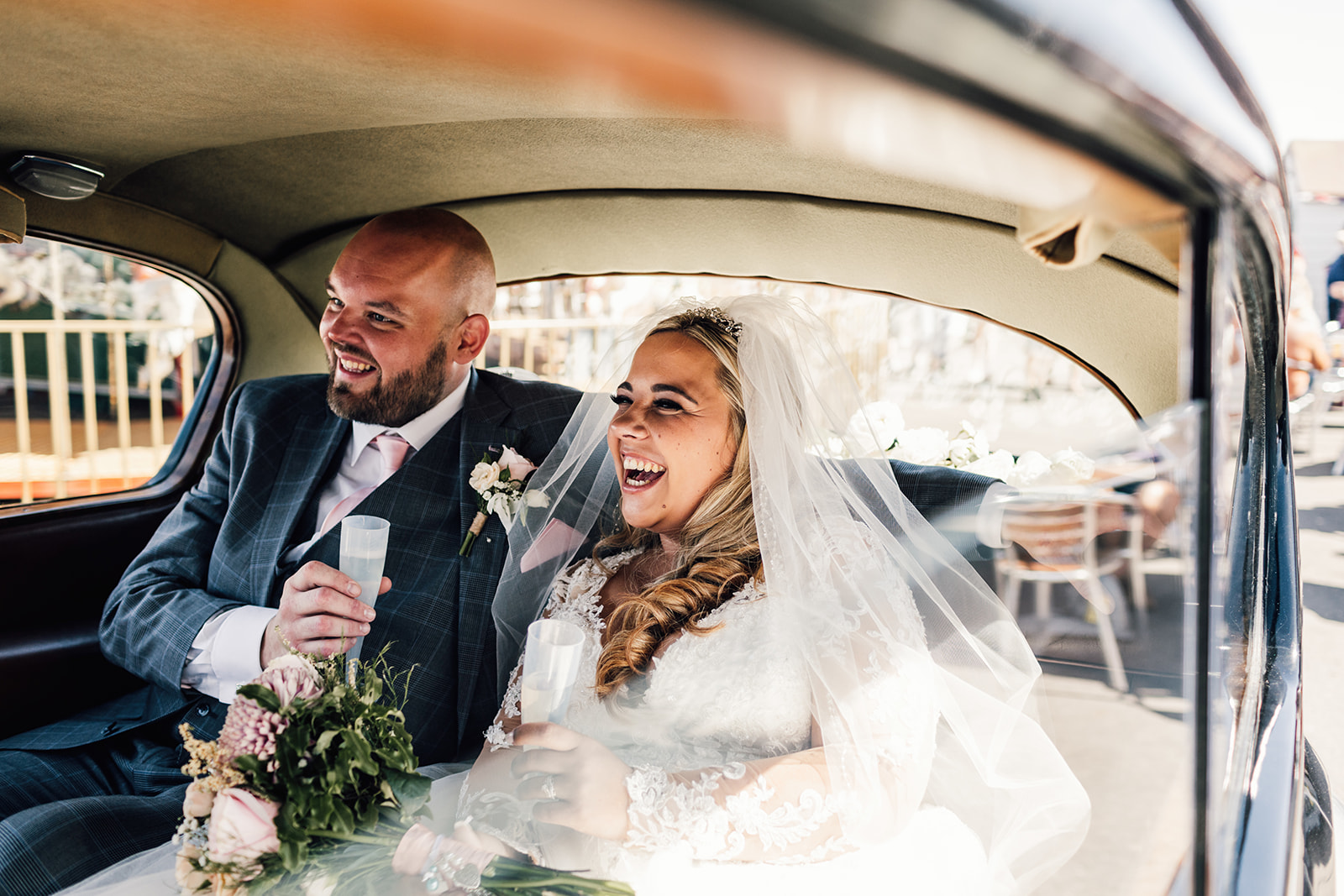 Portrait of couple laughing with champagne in vintage car