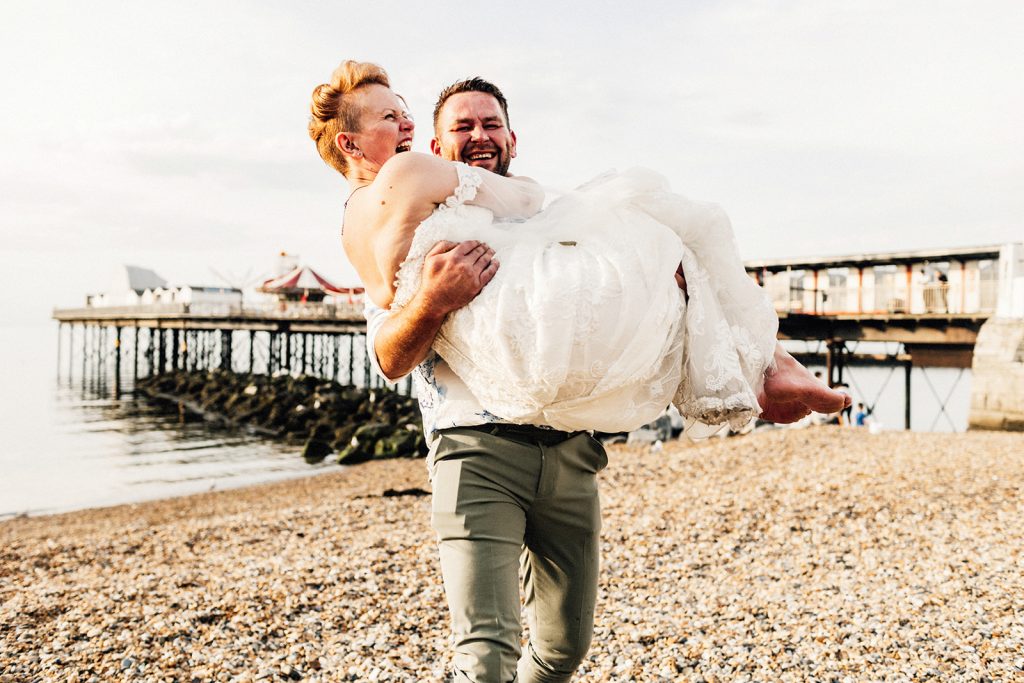 bride and groom portrait with groom carrying bride on Herne Bay beach