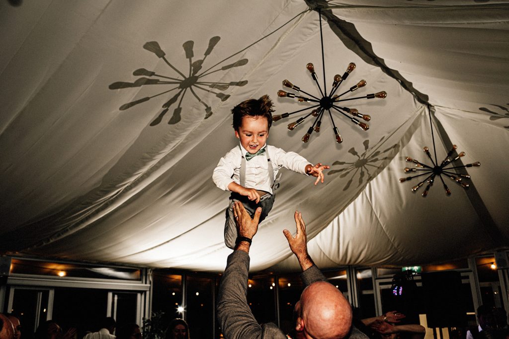 small boy being thrown up into the air on the dance floor at a wedding at the Night Yard wedding venue