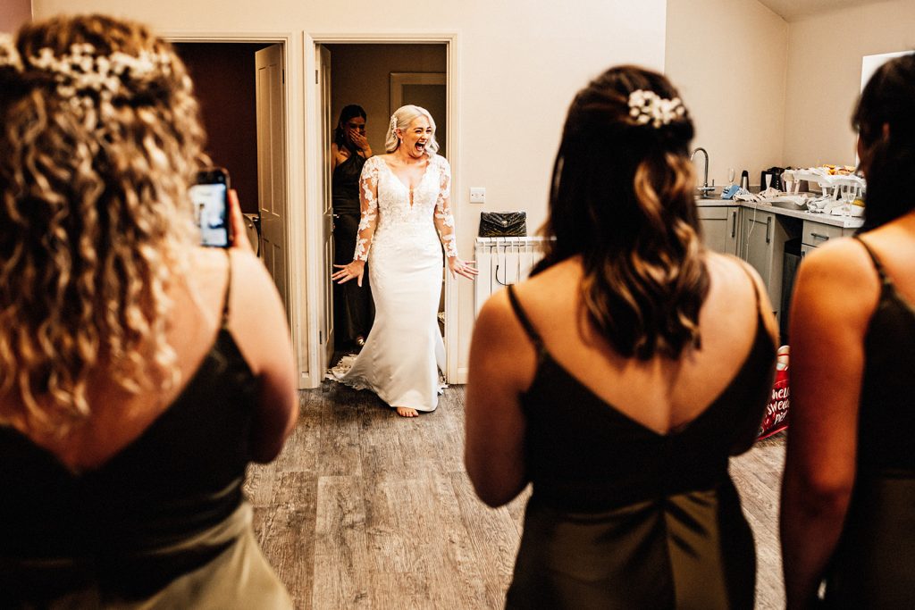 bride revealing her dress in front of her bridesmaids at winters barns wedding venue