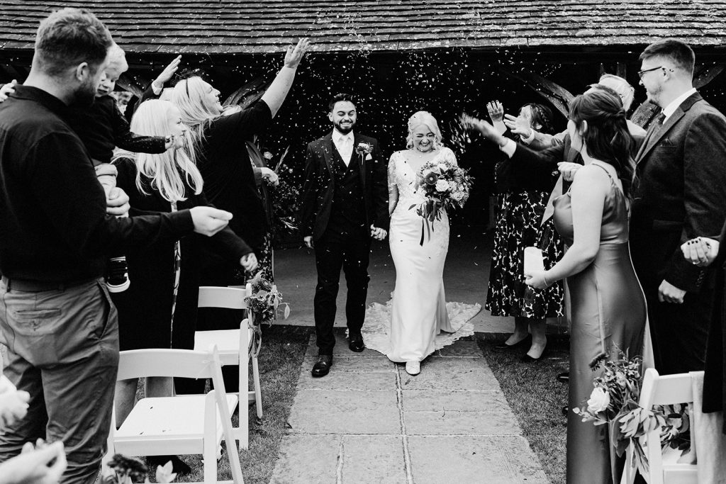outdoor confetti exit with guests throwing confetti over bride and groom at winters barns wedding venue