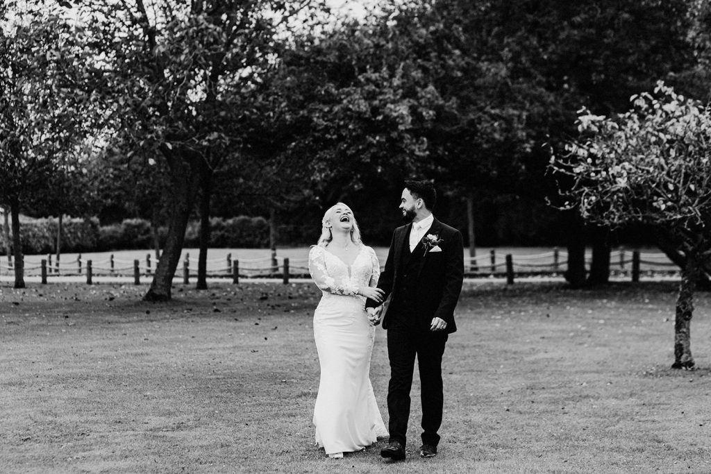 bride and groom laughing and smiling walking together in the grounds of winters barns wedding venue
