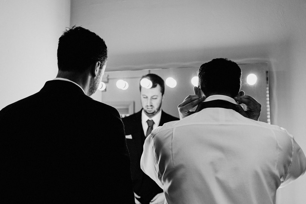 groomsmen getting ready using mirror with lights at winters barns wedding venue