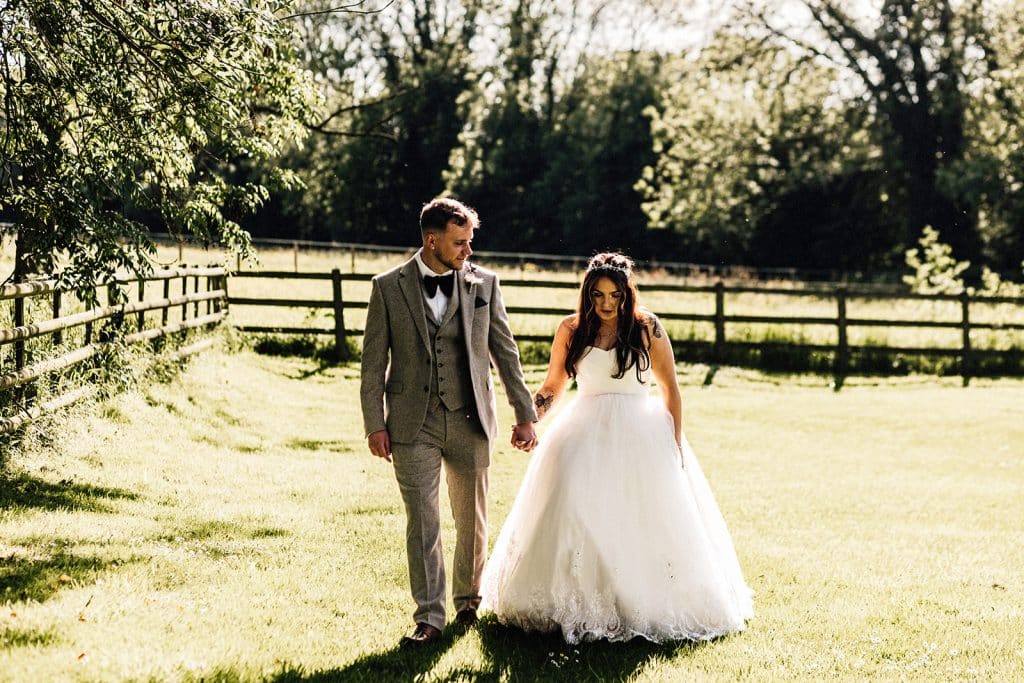 couple portrait of bride and groom walking towards camera holding hands captured by Chilham Village Hall wedding photographer