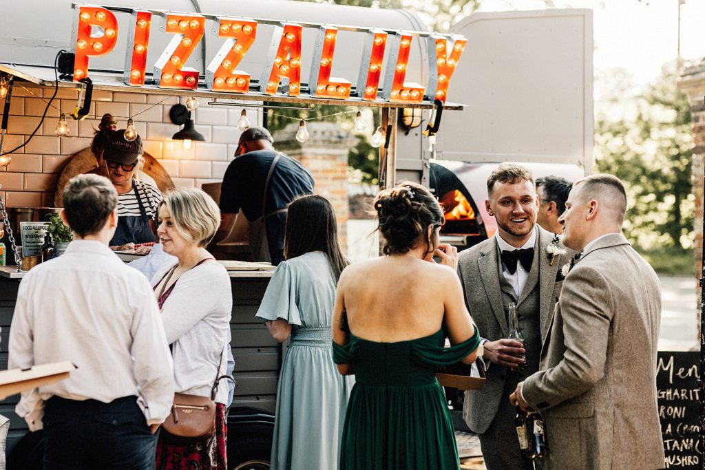 groom chatting with wedding guests outside taken by Chilham Village Hall wedding Photographer