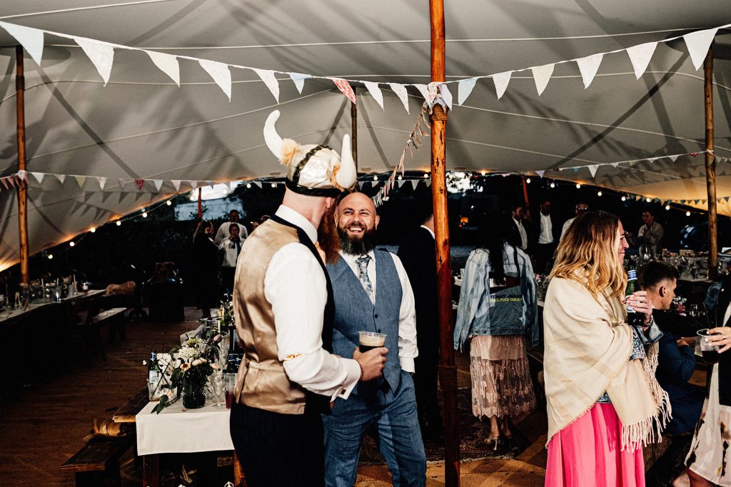 Groom in tipi at wedding wearing a viking helmet