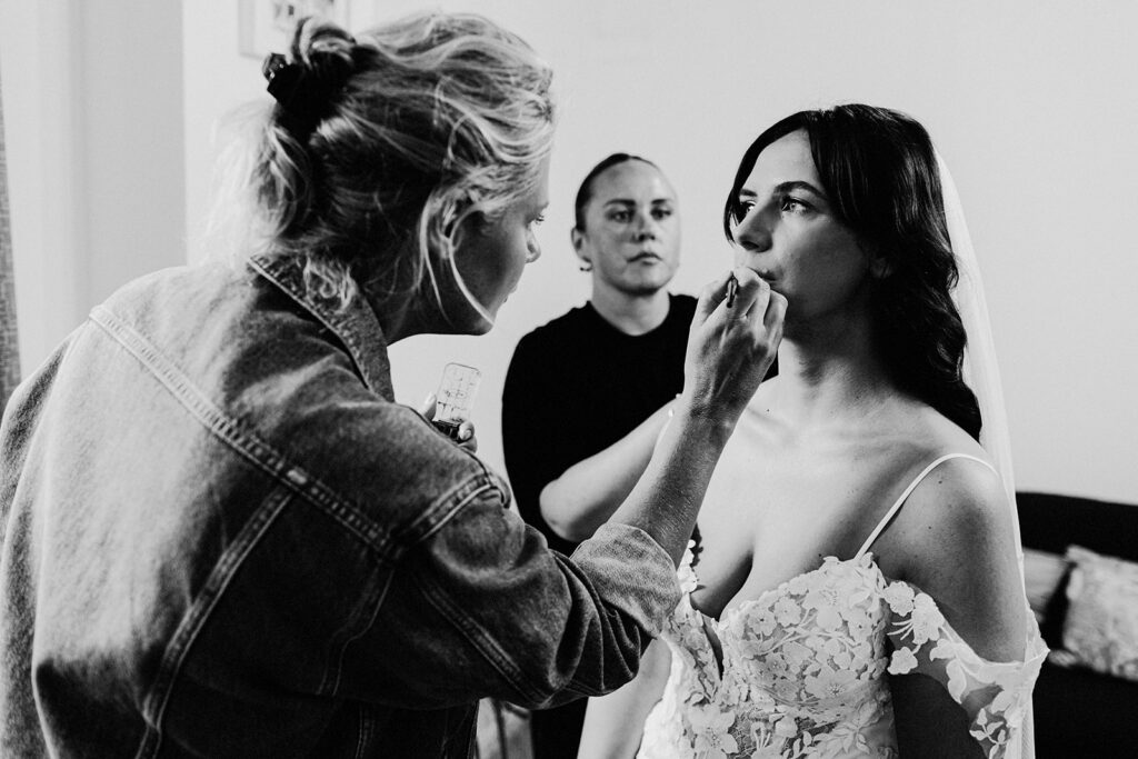 bride having finishing touches to her lips by mua at a Swarling Manor wedding.