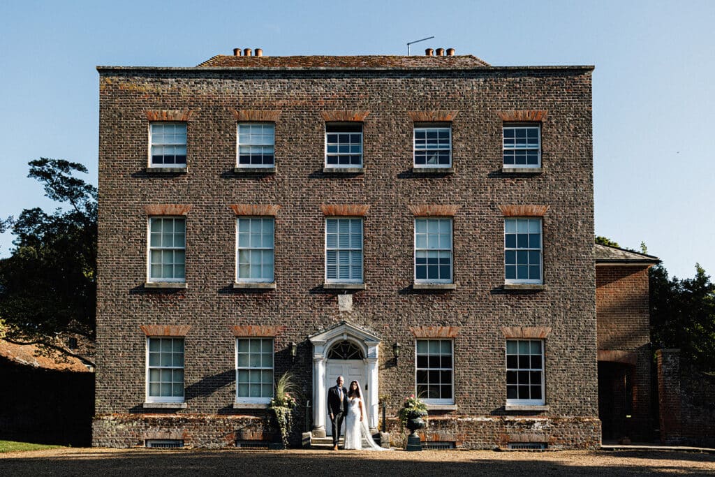 bride and groom wedding portrait in front of the Manor house in the grounds of Swarling manor.