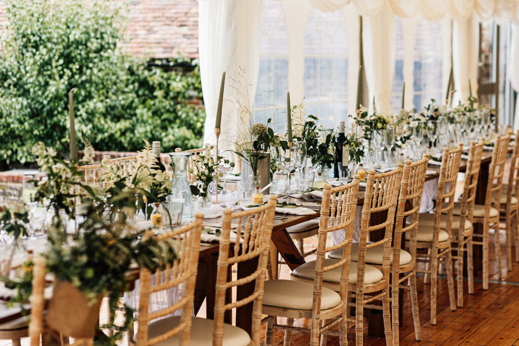 a long table dressed with flowers and candles in a green and white colour scheme in the marquee at Swarling manor wedding venue.
