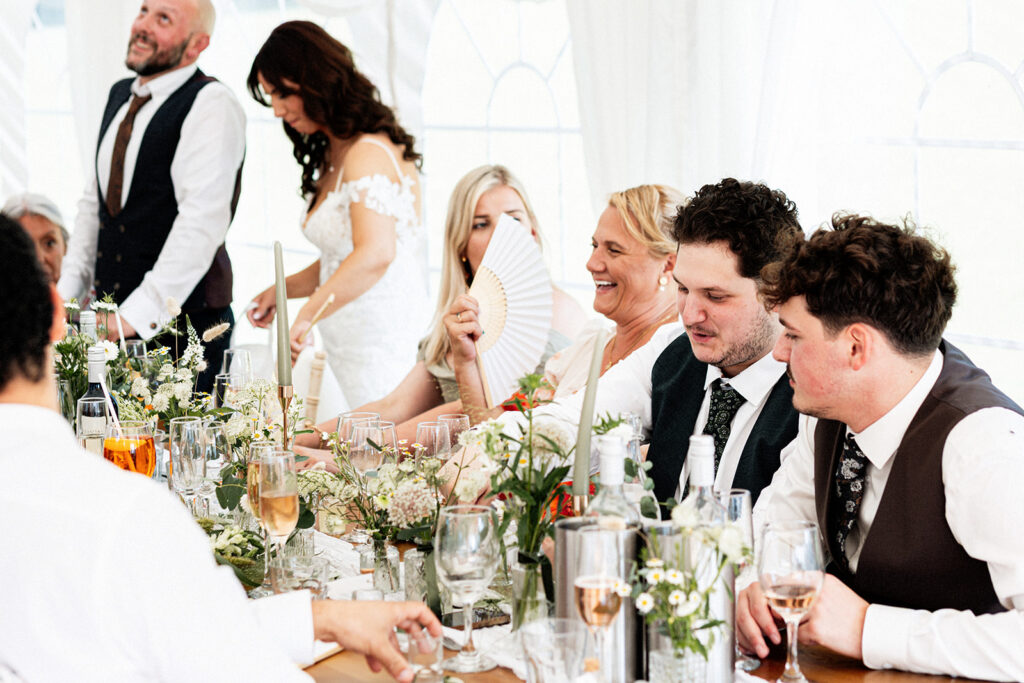 wedding guests laughing and chatting at wedding breakfast at Swarling Manor wedding venue