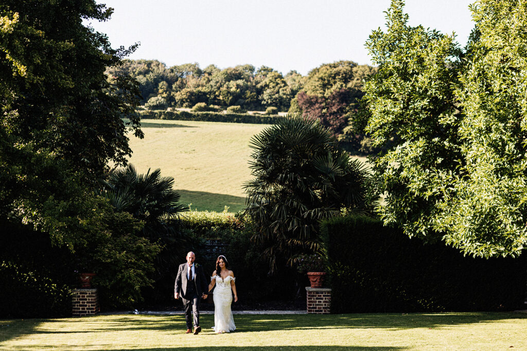 wedding portrait of bride and groom in the landscaped gardens of Swarling Manor wedding venue with rolling hills and fields in the background.